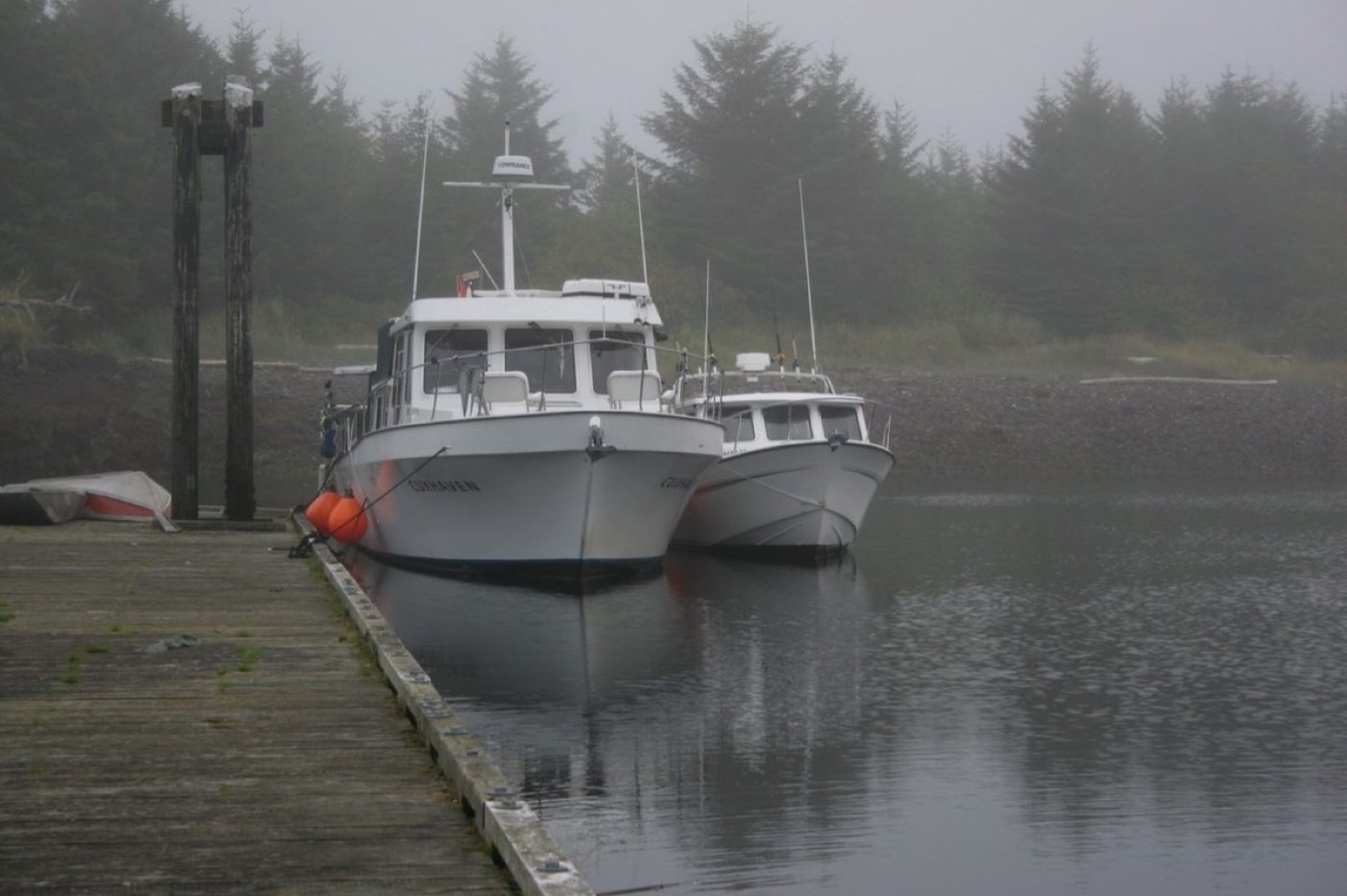 Fishing boats at a wooden dock on a foggy north-coast morning